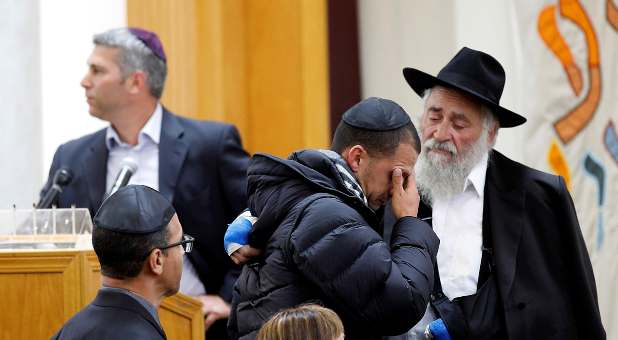 Rabbi Yisroel Goldstein (R), his hand still bandaged, consoles a man at the funeral for Lori Gilbert-Kaye.