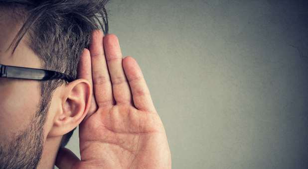 man with hand to ear
