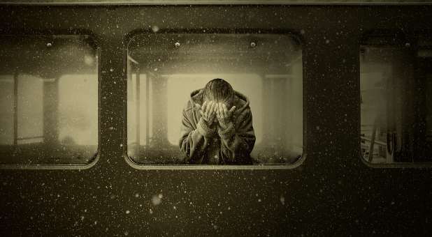 Woman in train window, head in hands